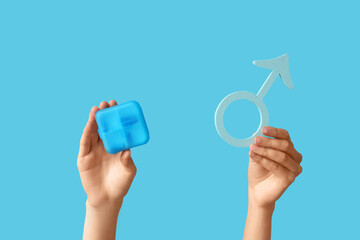 Female hands with pill box and symbol of man on blue background. Prostate Cancer Awareness Month
