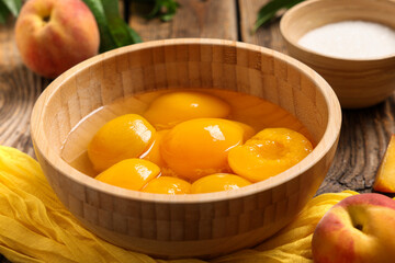 Bowls of tasty canned peaches and sugar on wooden table