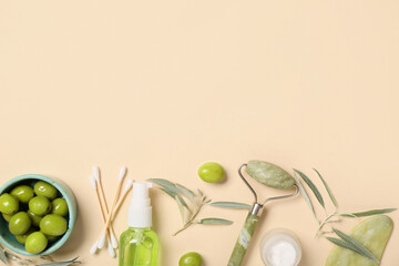 Composition with natural cosmetic products, facial massage tools and green olives on color...
