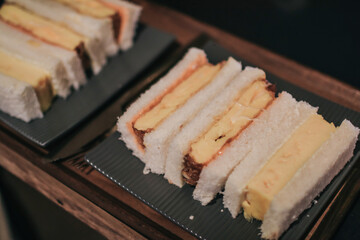 Sandwich with japanese omelet and pork. Tamako in bread on wooden tray. Morning breakfast.