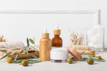 Set of natural cosmetic products, spa accessories and green olives on light table