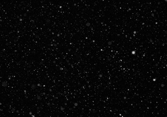 Fototapeta premium Falling snow particles on a dark black background, winter atmosphere