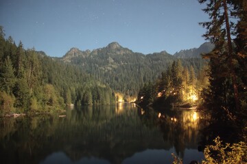 Fototapeta premium Nighttime lake scene with mountains and lights