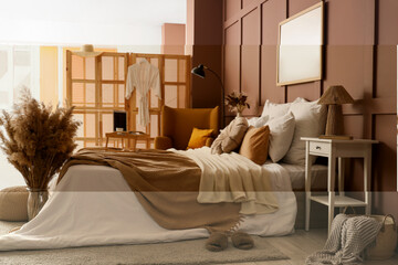 Interior of stylish bedroom with cozy bed, laptop and pampas grass