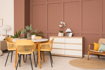 Interior of stylish living room with armchair, dresser and dining table