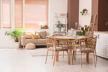 Interior of stylish open space kitchen with sofa, dining table and houseplants