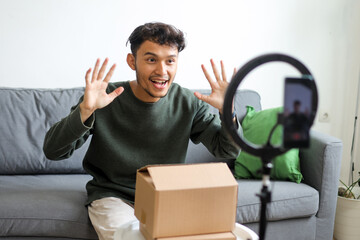 Excited Young Influencer Man Greeting With Waving Hands During Recording Video Using Smartphone