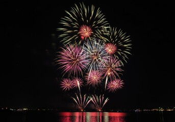Colorful fireworks explode in the night sky over water