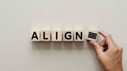 top-down shot of wooden cubes spelling align with a hand placing a cube featuring horizontal lines symbolizing alignment, design, and precision in layout, formatting, and organization concepts