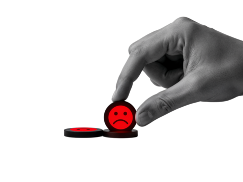 Close up of a human hand holding a small red circular object with a sad face symbol isolated on transparent background