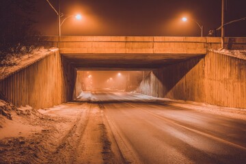 Empty highway underpass at night, snow, muted orange light