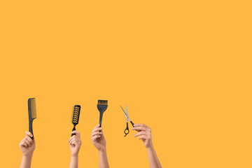 Female hands with different hairdresser's supplies on orange background