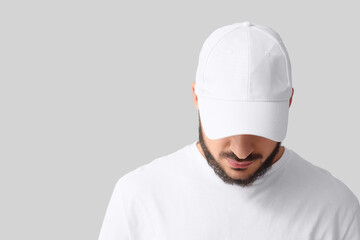 Handsome young man in stylish cap on grey background