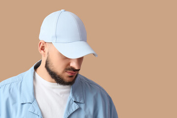 Handsome young man in stylish cap on beige background