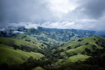 Fototapeta premium Lush green hills under a cloudy sky