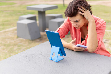 Woman looking concerned while attending a virtual call outside
