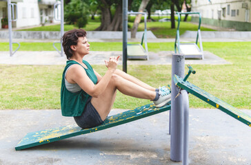 Woman getting fit with sit up exercises in a natural park with public gym