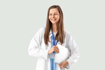 Female medical intern with laptop on light background