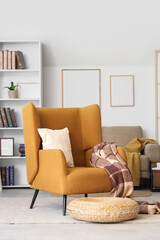 Interior of stylish living room with brown armchair, wicker pouf and bookshelf
