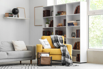Interior of stylish living room with yellow armchair, grey sofa and bookshelf