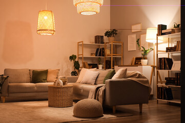 Interior of stylish living room with grey sofas, glowing lamps and bookshelves at evening © Pixel-Shot