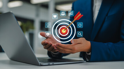 Businessman holding target with arrow and digital icons above laptop success goal