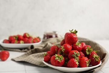 Plates with sweet ripe strawberries on white tile table
