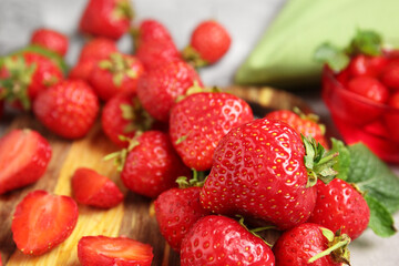 Wooden board with sweet ripe strawberries on grey background, closeup