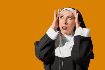 Shocked mature woman dressed as nun on yellow background. Halloween celebration
