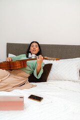 Singer songwriter composing new music on acoustic guitar in bedroom
