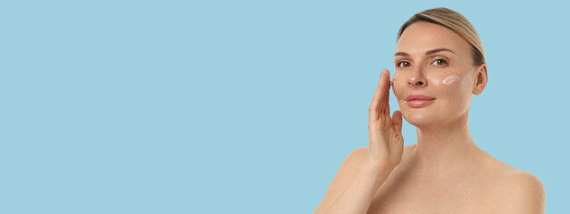 Woman applies skincare cream to her face calmly