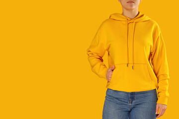 Woman in yellow hoodie and jeans, colorful backdrop