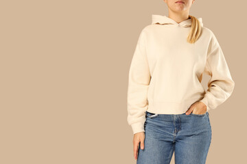 Model in beige hoodie and jeans on neutral backdrop