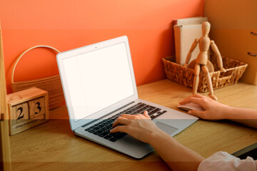Young woman using modern laptop with blank screen at table in home office, closeup
