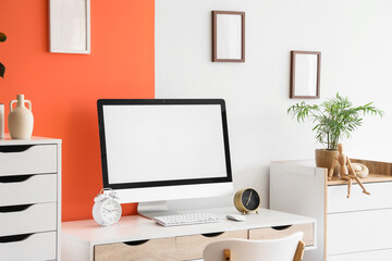Comfortable workspace with modern computer, alarm clocks and houseplant near color wall, closeup