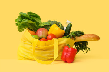 Net bag with different groceries on yellow background, closeup