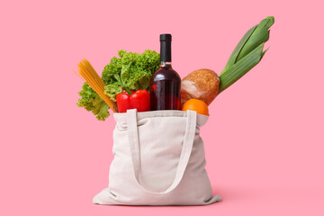 Eco bag with different groceries on pink background