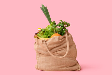 Eco bag with different groceries on pink background