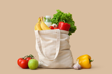 Eco bag with different groceries on beige background