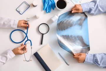 Doctors with x-ray image and stethoscope working at white table, top view