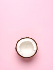 A clean and minimalist top-down view of a fresh half coconut. The natural texture and white flesh contrast with the simple pink background, creating a modern, tropical, and healthy food design.
