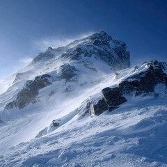 Snow-covered mountain peak under a vibrant blue sky; windswept snow