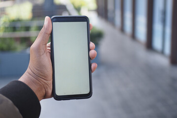 Hand holding a smartphone in a modern outdoor setting