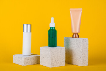 Plastic white tube for cream or lotion. Skin care or sunscreen cosmetic with stylish props on yellow background.