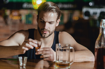 Man sitting alone in pub. Man with alcohol. Sad guy in bar. Guy in dark bar. Alcohol problem. Lonely man drinking whiskey at restaurant. Depressed man with glass of beer. Nightlife club.