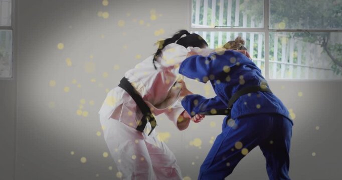 White-gi athlete gripping lapel and hip throwing blue-gi partner in sparring golden sparks drifting