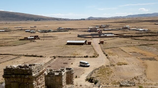 Explore the ancient Chullpas de Molloco archaeological site in Peru with this tilt shot. Unique stone tombs set within a vast, dry landscape under a clear sky