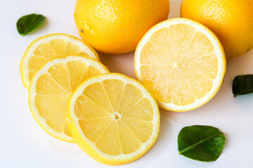Fresh and vibrant lemons, accompanied by a couple of lemon slices, set against a clean white...