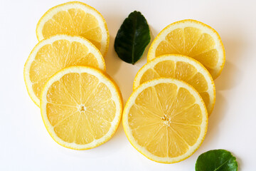Bright, juicy slices of fresh lemon, artfully arranged on a clean white background with scattered...