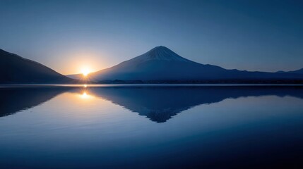 Serene sunrise casts a golden glow on mountain peak reflected in calm waters